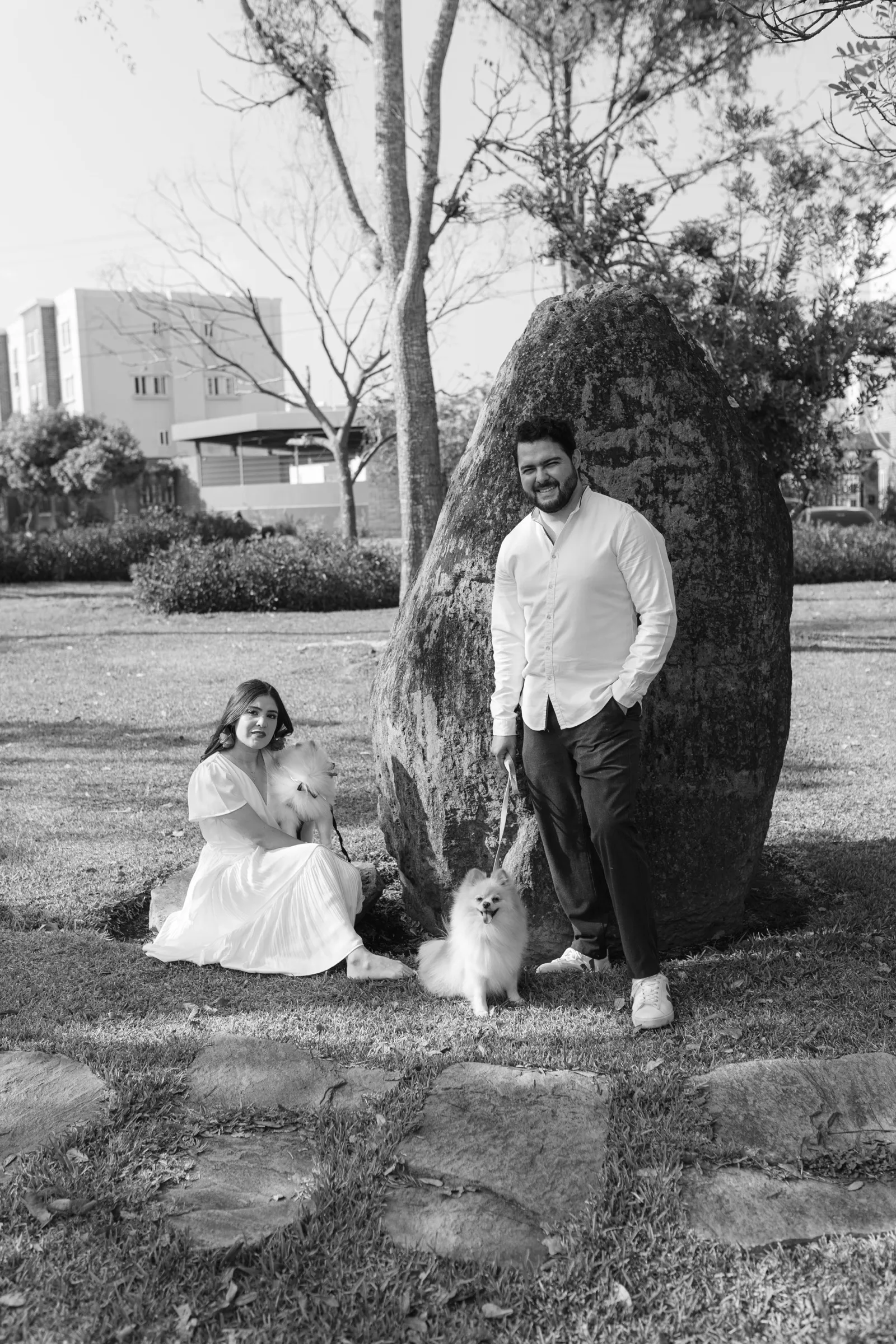 Fotografía en blanco y negro de Josué y Katherine con su perro junto a una roca